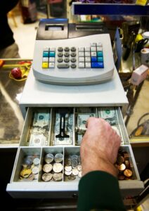 Picture of an employee with their hand in the till